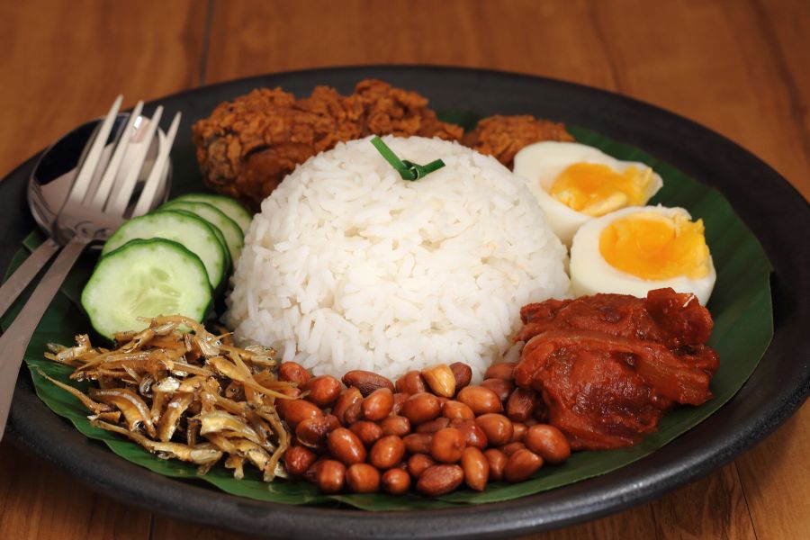 A bowl of Hokkien Prawn Mee with rich broth, noodles, prawns, hard-boiled egg, and a side of sambal chili paste
