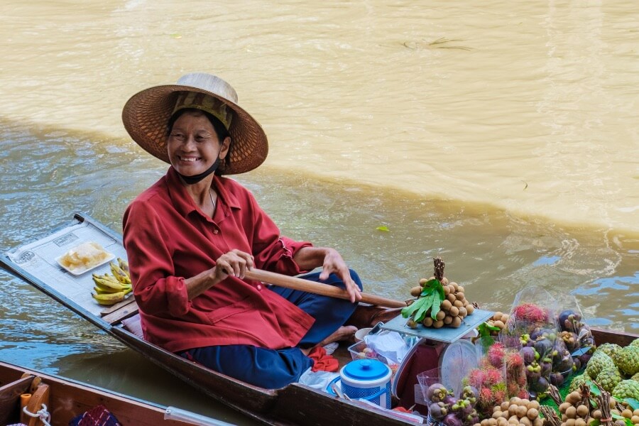 Thai lady sitting on boat at Damnoen Saduak floating market selling fruits