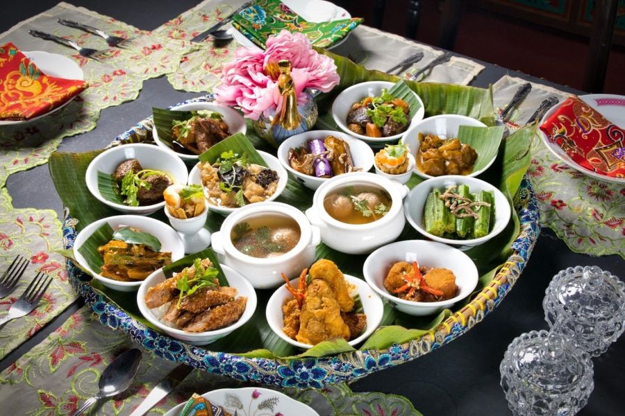 Peranakan feast with assorted Nyonya dishes in small bowls on a large tray